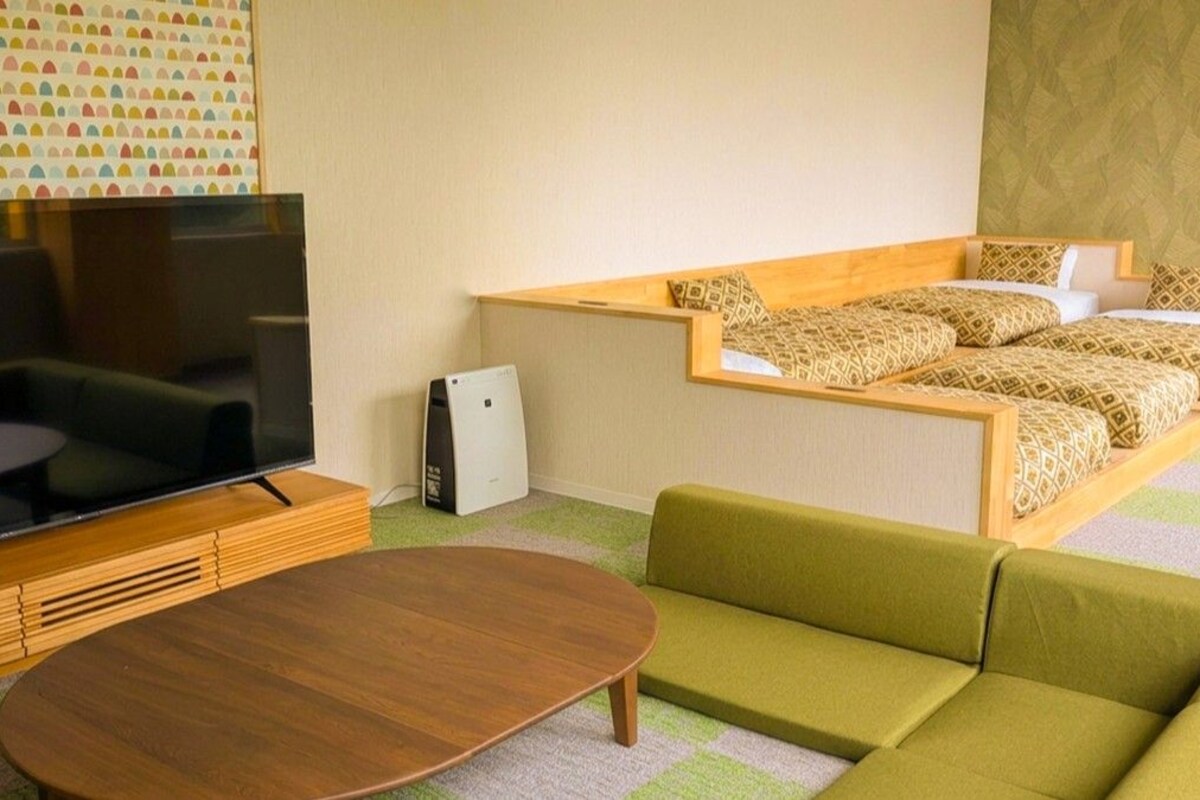 A hotel room with a television, sofa, and a bed with patterned bedding.