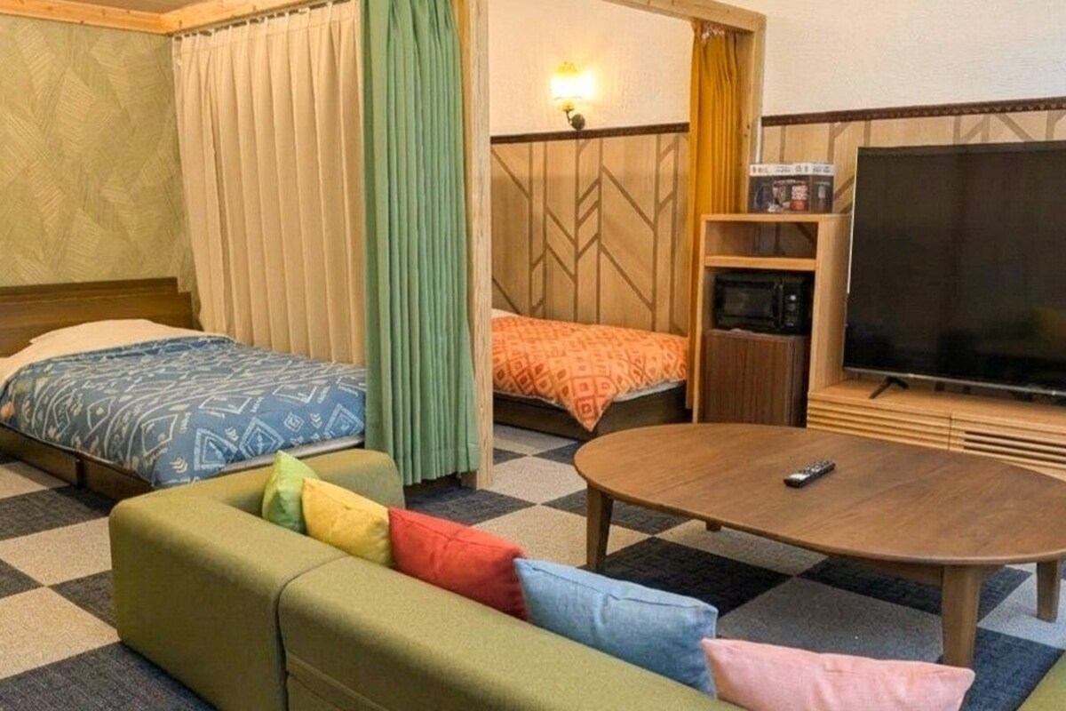 A hotel room with a bed, a sofa, a TV, and a small table.