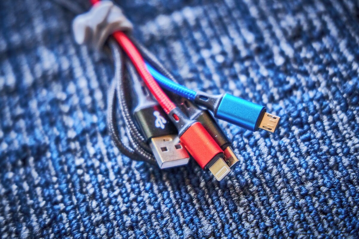 A USB cable with red, blue, and black connectors on a textured fabric surface.