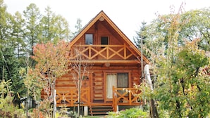 A wooden cabin with a balcony, surrounded by trees. - Rental Log Cottage West Village (Gujo)