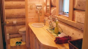 A wooden cabin bathroom with a wooden sink, toilet, and shower area. - Rental Log Cottage West Village (Gujo)
