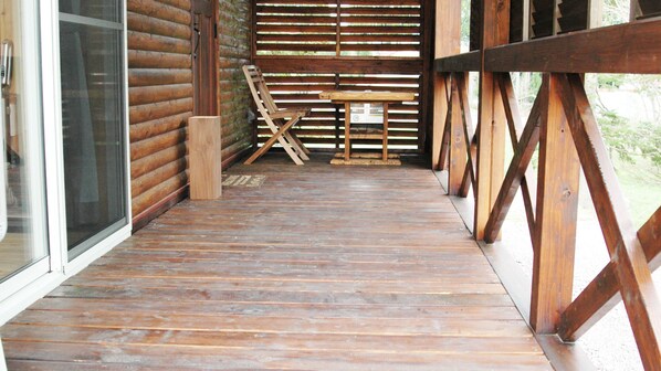 A wooden deck with a table and chairs, a window, and a door. - Rental Log Cottage West Village (Gujo)
