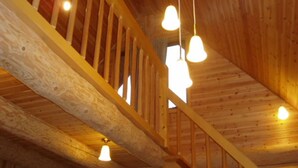 A wooden interior with a staircase and hanging light fixtures. - Rental Log Cottage West Village (Gujo)