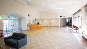 A spacious lobby with a reception desk, a blue sofa, and a checkered floor. - Etoile Oishi (Sumoto)