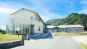 A modern building with a curved glass facade, a covered outdoor area, and a traditional building with a tiled roof. - Etoile Oishi (Sumoto)