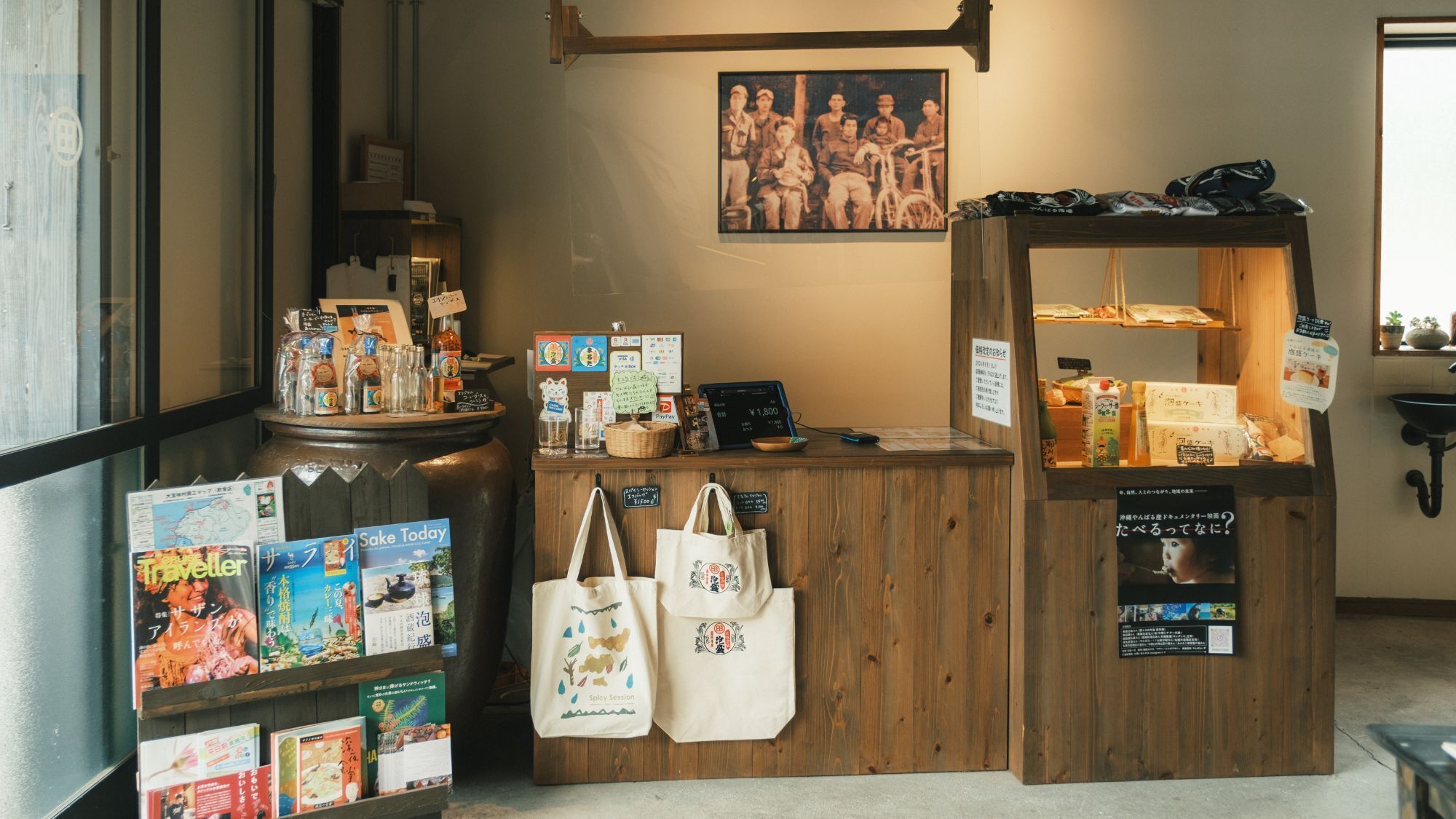 A wooden counter with a cash register, a vintage photo, and a display of food items.
