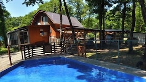 Ein Schwimmbecken mit Holzterrasse und einem Haus im Hintergrund.
