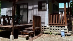 Ein Haus mit blauem Dach, einer Holzveranda und einem eingezäunten Garten.
