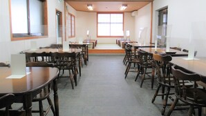A conference room with multiple tables and chairs, large windows, and ceiling lights. - Business Hotel Mikumo (Konan)