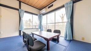 A room with a large table, two chairs, and a blue mat on the floor. - Iu Workation (Ito)