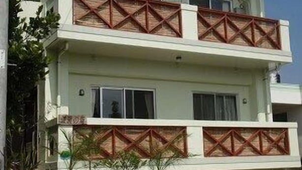Un edificio de dos pisos con un balcón en el nivel superior.