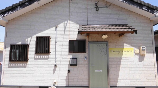 Un edificio con techo de tejas, puerta verde y un letrero que dice "Mariage maison".