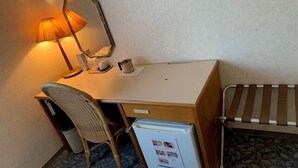A compact hotel room with a wooden desk, a chair, a small refrigerator, a bedside table, and a lamp. - Toyo Shirahama Resort Hotel (Toyo)