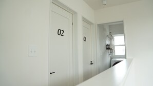 Un couloir avec des portes numérotées, une fenêtre et un radiateur.