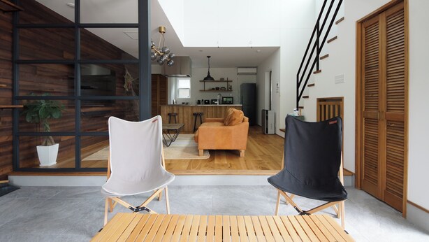 Un salon moderne avec un canapé, deux fauteuils, une table en bois et une grande fenêtre.