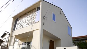 Un bâtiment à deux étages avec une façade en pierre, une enseigne indiquant qu’il s’agit d’un centre de vacances pour animaux de compagnie, et une petite porte d’entrée.