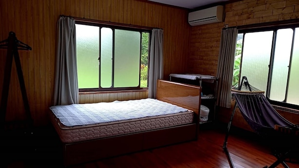 A room with a bed, a hammock, and a window with curtains. - Amami no Yado Good Green (Setouchi)