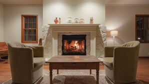 A living room with a fireplace, two armchairs, a coffee table, and a patterned rug. - The Rura (Maebashi)