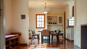 A dining area with a wooden table, chairs, and a hanging light fixture. - The Rura (Maebashi)