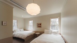 A bedroom with two beds, a round table, and a hanging light fixture. - The Rura (Maebashi)