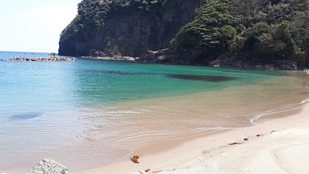 A beach with clear turquoise water, sandy shore, and rocky cliffs. - Moritasanchi (Ine)