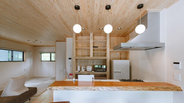 Eine moderne Küche mit Holzschränken, einer Marmorarbeitsplatte und einer Kochinsel mit Barhocker.