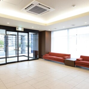 A spacious lobby with a red sofa, a small table, and a glass door entrance. - AB Hotel Kani (Kani)