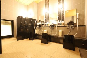 Un baño moderno con varios lavamanos, espejos y secadores de pelo.