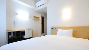 A hotel room with a bed, a desk, a chair, a wardrobe, and an air conditioning unit. - AB Hotel Kani (Kani)