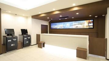 A hotel reception area with a digital display, reception desk, and two card machines.