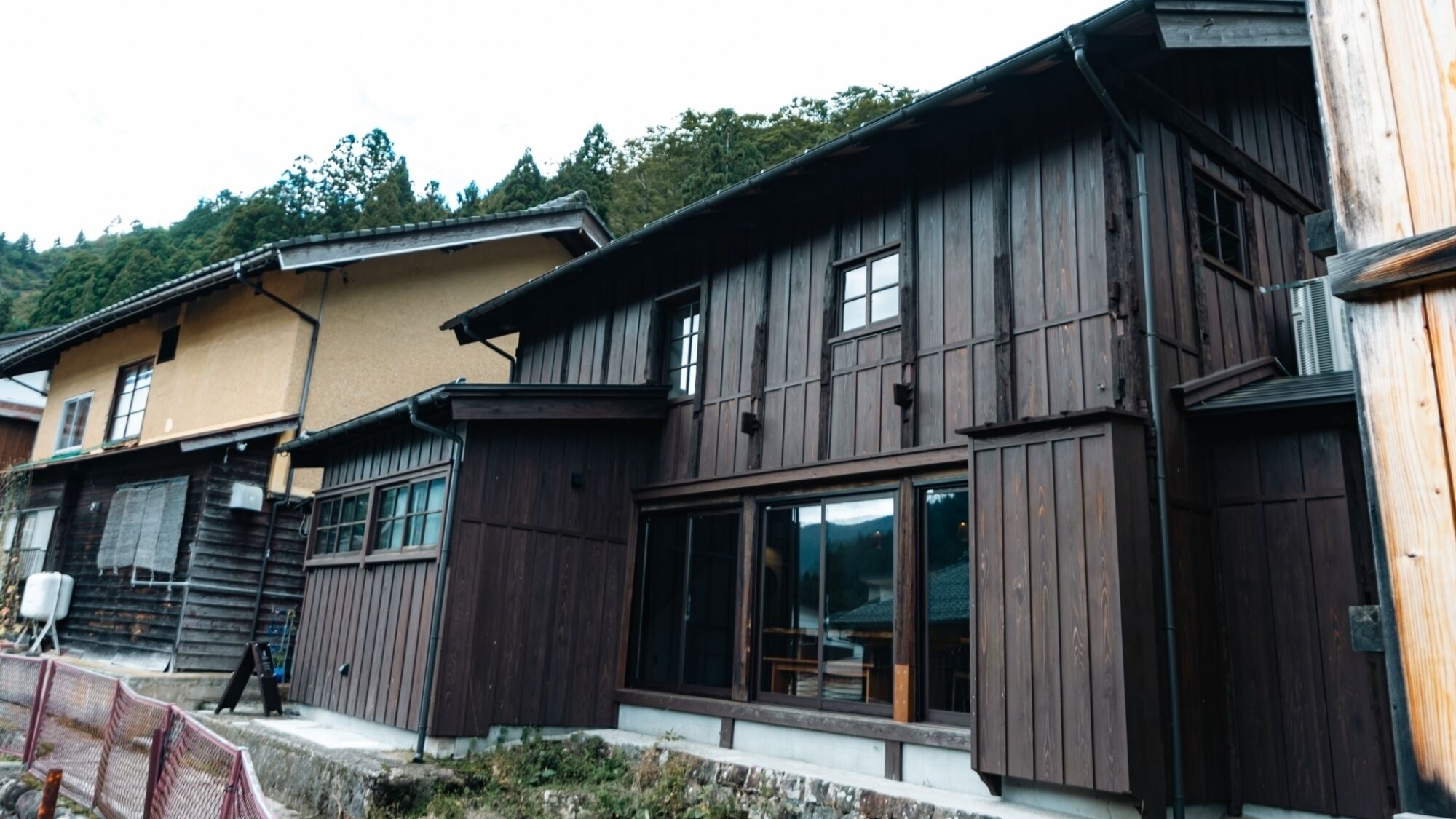 Une maison traditionnelle en bois, dotée de grandes fenêtres et d’un balcon.