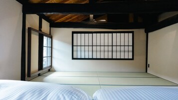 A traditional Japanese-style room with tatami flooring, a shoji screen, and a low ceiling with exposed beams.