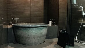 A modern bathroom with a large freestanding bathtub, a glass shower enclosure, and a small shelf with toiletries. - Nipponia Hakusanshiramine Okuyamabitonosato Sennyomoto (Hakusan)