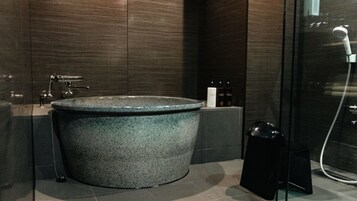 A modern bathroom with a large freestanding bathtub, a glass shower enclosure, and a small shelf with toiletries.