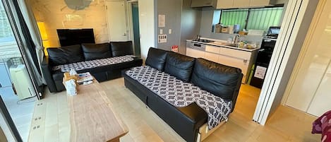 Een moderne woonkamer met een zithoek, een salontafel en een keuken die zichtbaar is door een open deur.