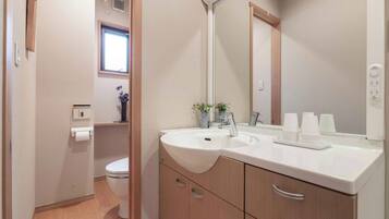 A modern bathroom with a white sink, a mirror, and a toilet.