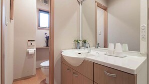 A modern bathroom with a white sink, a mirror, and a toilet. - Temple Hotel Matsui-bo (Minobu)