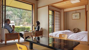 Ein traditioneller japanischer Raum mit Tatami-Bodenbelag, einem niedrigen Tisch und einem Bett mit Futon.