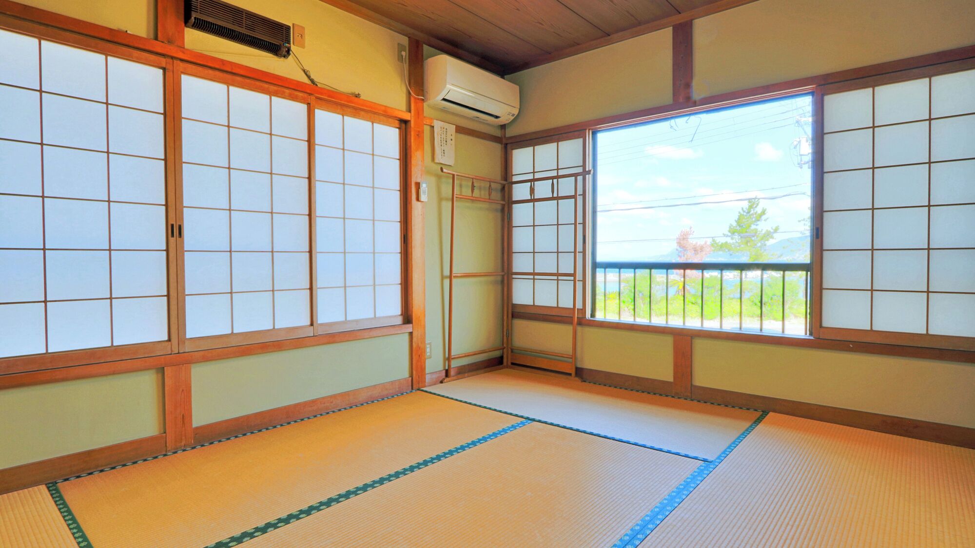 A traditional Japanese room with tatami flooring, sliding doors, and a view of a balcony.