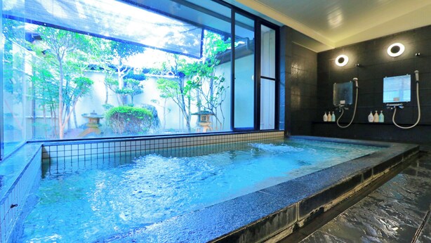 Un bain à remous avec vue sur un jardin et une lanterne japonaise traditionnelle.