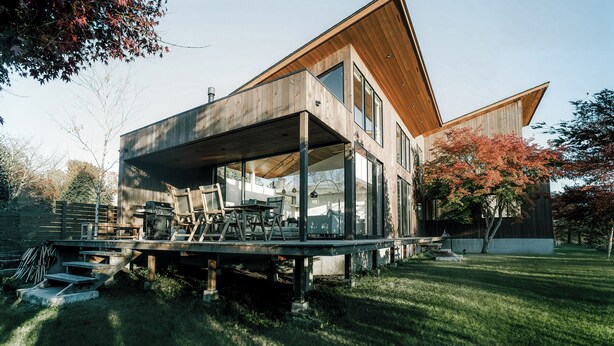 A modern house with a wooden exterior, large windows, and a deck area. - Sukh (Karuizawa)