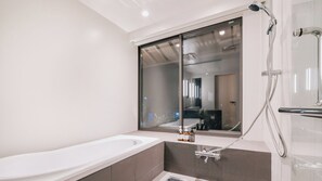 Een moderne badkamer met een badkuip, een glazen douchecabine en een raam.