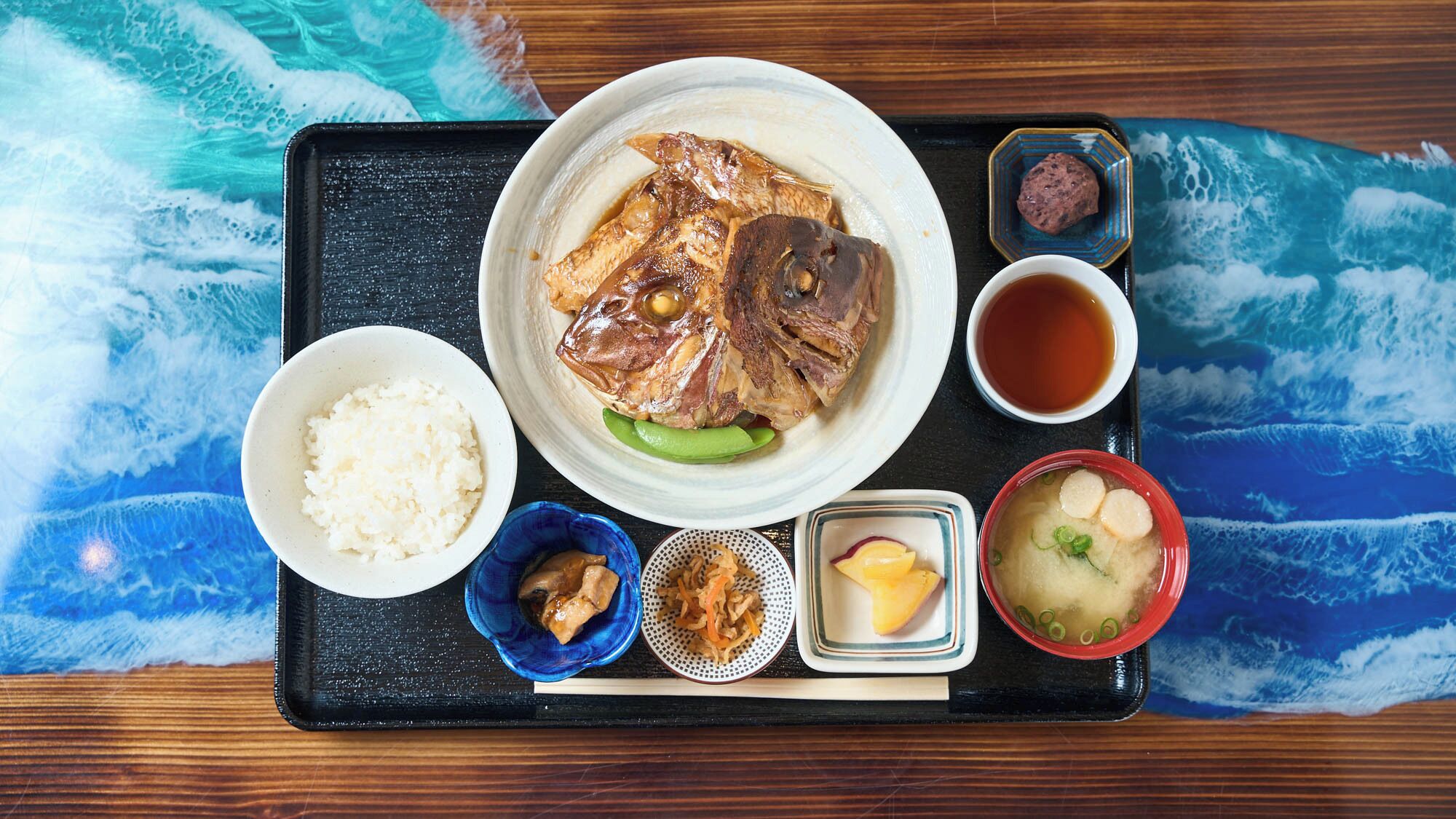 A traditional Japanese meal with rice, fish, and various side dishes on a tray.