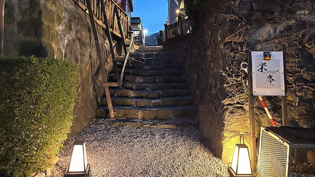 Eine enge Steintreppe führt zu einem Gebäude mit einem Schild.