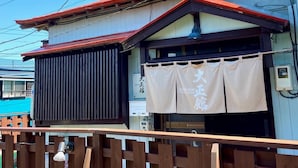 Ein traditionelles japanisches Gebäude mit einem Holzzaun im Vordergrund.