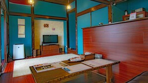 Ein Zimmer mit Holztisch, Fernseher und kleinem Kühlschrank.