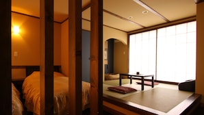 A traditional Japanese-style room with tatami flooring, a low wooden bed, and a sliding shoji screen door. - Mutsumian (Kawazu)