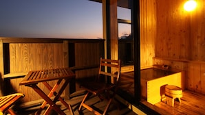 A wooden deck with a table and chairs, a wooden bench, and a small stool. - Mutsumian (Kawazu)