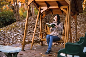 A wooden swing chair in a park with a person reading a book. - Log Cottage Chausu no Mori (Nasu)