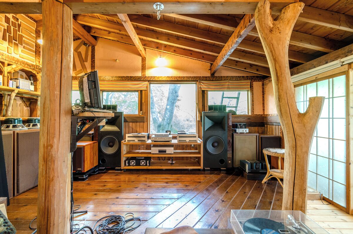Ein rustikales Blockhaus-Interieur mit Holzböden, einem großen Fenster und einer Holztreppe.